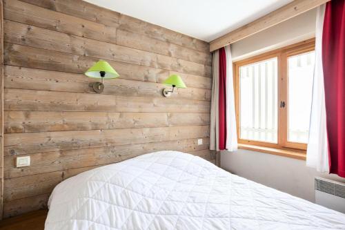 a bedroom with wooden walls and a bed with two lamps at Résidence Le Christiana - maeva Home - Appartement 2 Pièces 5 Personnes - Sélection MAE-3814 in Saint-Bon-Tarentaise