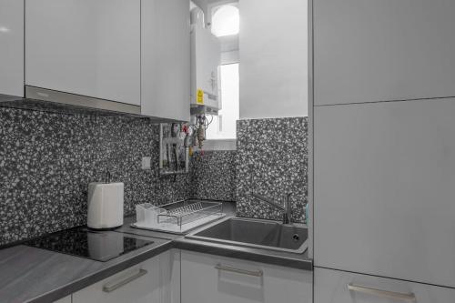 a kitchen with white cabinets and a sink at Amazing location - 2 min from Acropolis in Athens