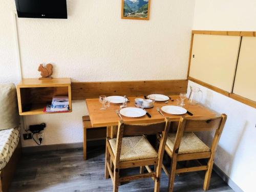 - une table en bois avec des chaises et des assiettes dans l'établissement Résidence Pierres Plates - Les Pierres Plates 51 - Studio divisible au pied des pistes MAE-4884, à Valmorel