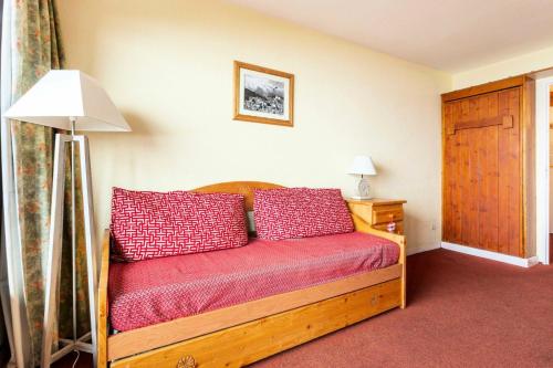- une chambre avec un lit en bois et des oreillers rouges dans l'établissement Résidences quartier Charmettoger - maeva Home - Appartement 2 pièces 5 personnes - Budget MAE-1884, à Arc 1800