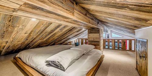 un grand lit dans une chambre aux murs en bois dans l'établissement Résidence Le Chardonnet - 4 Pièces pour 7 Personnes MAE-3299, à Champagny-en-Vanoise