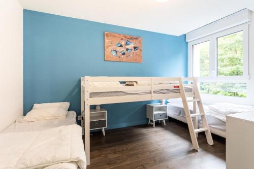 une chambre avec deux lits superposés et un mur bleu dans l'établissement Résidence les Chardons - maeva Home - Appartement 2 pièces 5 personnes - Confort MAE-4014, à Arc 1800