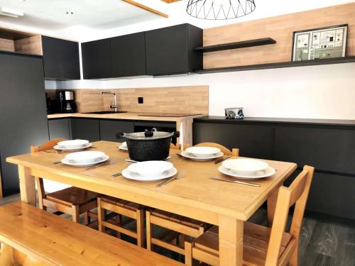 une cuisine avec une table en bois, des assiettes et des chaises dans l'établissement Résidence Valeriane - La Valériane 106 - Joli 3 pièces rénové, idéalement situé MAE-5414, à Valmorel