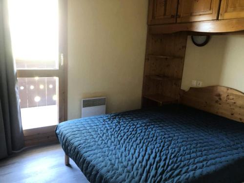 une chambre avec un lit avec une couette bleue et une fenêtre dans l'établissement Résidence Valeriane - La Valériane 213 - 3 pièces avec vue magnifique sur les montagnes MAE-5424, à Valmorel