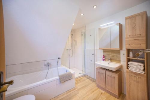 ein weißes Badezimmer mit einer Badewanne und einem Waschbecken in der Unterkunft Ferienhaus OG2 "Bönsberg Blick" in Martinfeld