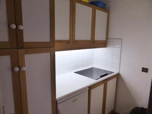 une cuisine avec un comptoir blanc et des placards en bois dans l'établissement Résidence Souche - La Souche 9 - Grand 2 pièces, proche de la rue piétonne MAE-4844, à Valmorel