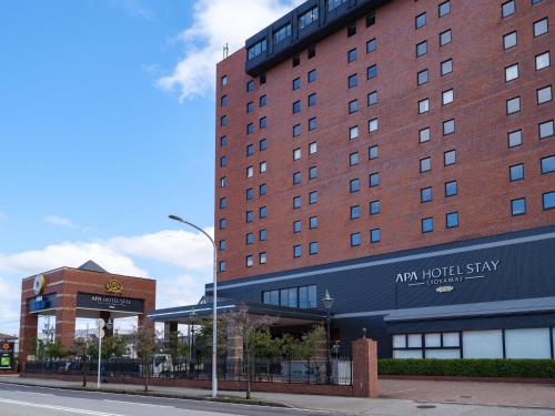 un bâtiment avec un hôtel sur le côté d'une rue dans l'établissement APA Hotel STAY Toyama, à Toyama