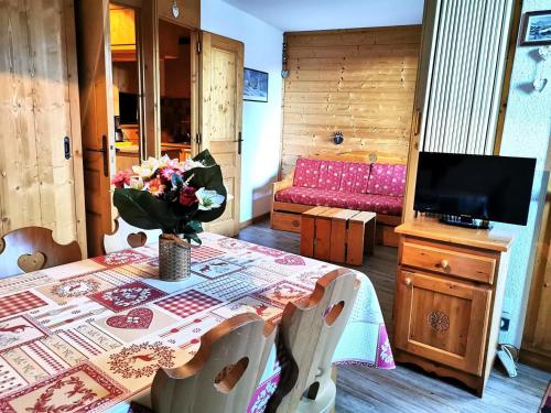une salle à manger avec une table et un vase de fleurs. dans l'établissement Résidence Clairiere - La Clairière 33 - Joli studio divisible, calme, classé 2 étoiles MAE-5204, à Valmorel