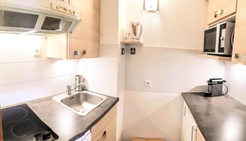 une cuisine avec un évier et un micro-ondes dans l'établissement Résidence Lauziere Dessous - La Lauzière-Dessous 22 - Joli 2 pièces divisible, ski aux pieds MAE-5444, à Valmorel