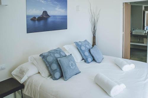 Una cama blanca con almohadas azules encima. en Can Albano - Santa Eulalia, en Santa Eulària des Riu