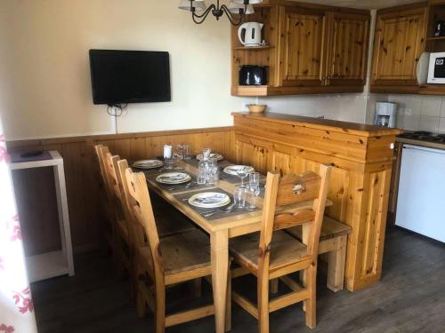 Il comprend une cuisine avec une table en bois, des chaises et une télévision. dans l'établissement Résidence Valeriane - La Valériane 214 - Joli 3 pièces proche des pistes et du bourg MAE-5494, à Valmorel