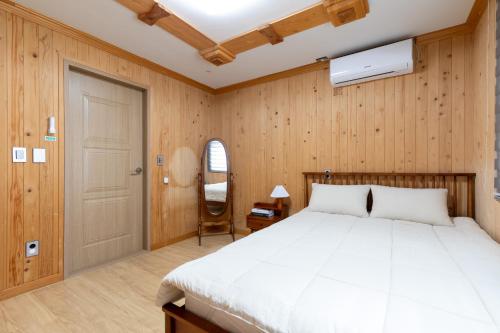 1 dormitorio con cama, puerta y silla en Bijarim Healing Pension en Jeju