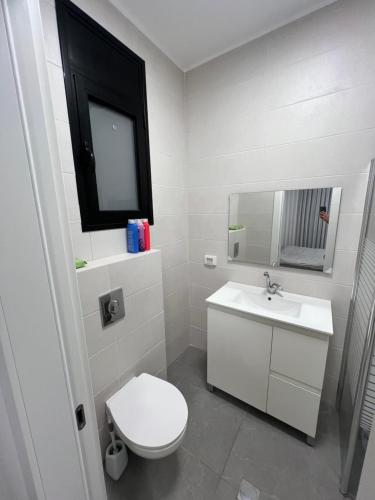 a bathroom with a white toilet and a sink at בית בים in Netanya