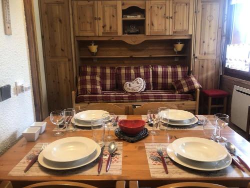 une table en bois avec des assiettes et des verres à vin dessus dans l'établissement Résidence Buche - La bûche 4 - Studio divisible, douillet, classé 2 étoiles MAE-5724, à Valmorel