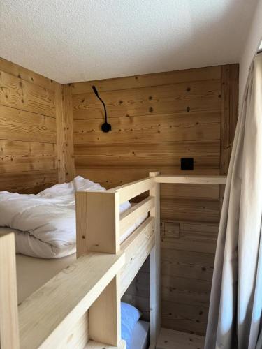 une chambre avec un lit et un mur en bois dans l'établissement Résidence Les Constellations - maeva Home - Studio 4 Personnes - Confort MAE-2024, à La Plagne Tarentaise