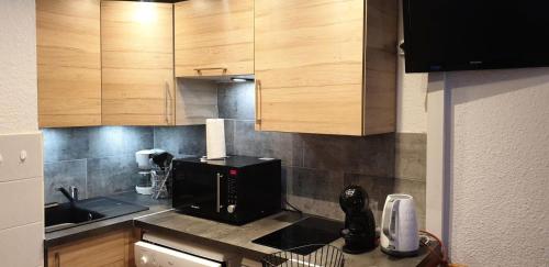 une cuisine avec des armoires en bois et un micro-ondes noir dans l'établissement Résidence Pierrer - Le Pierrer 51 - Studio divisible joliment rénové, classé 2 étoiles MAE-4044, à Valmorel