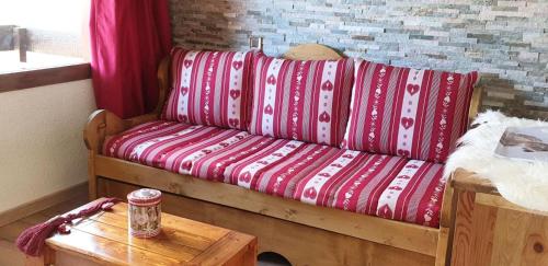 - un canapé avec des draps rouges et blancs dans l'établissement Résidence Pierrer - Le Pierrer 51 - Studio divisible joliment rénové, classé 2 étoiles MAE-4044, à Valmorel