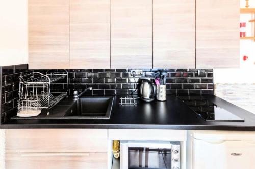 - une cuisine avec un plan de travail noir et un évier dans l'établissement Appartement à l'Alpe d'Huez retour skis aux pieds - maeva Home - Appartement skis aux pieds vue montagne 2 pièces 5 personnes - Sélection MAE-2614, à Huez