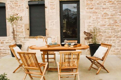 a patio with a wooden table and four chairs at Les Blés Dorés et Les Graines de Lin, 2 gîtes à la Ferme avec moutons et piscine, à côté de Beaune in Corgengoux