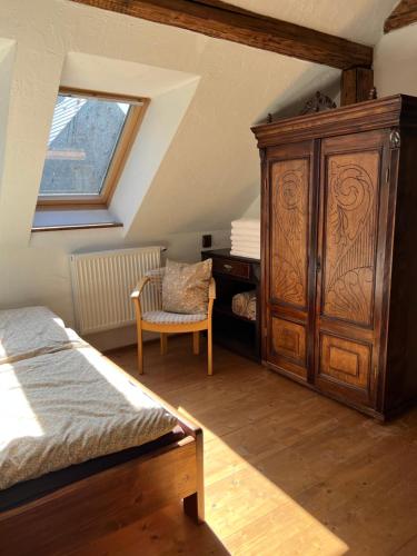 a bedroom with a large wooden cabinet and a chair at folk cottage Vysna Boca in Vyšná Boca