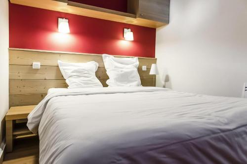 Mâcot La PlagneにあるRésidence Plagne Lauze - maeva Home - Appartement 2 pièces 5 personnes - S 984の赤い壁のベッドルーム1室(白い大型ベッド1台付)