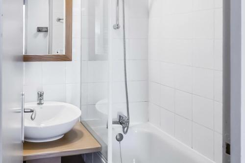 une salle de bain blanche avec un lavabo et une baignoire dans l'établissement Résidence Plagne Lauze - maeva Home - Appartement 2 pièces 5 personnes - Prestige MAE-0984, à Mâcot La Plagne