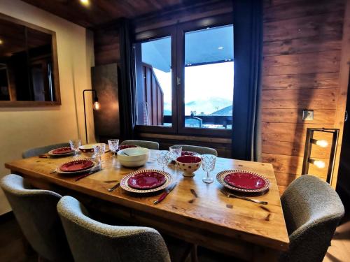 - une table en bois avec des chaises, des assiettes et des verres dans l'établissement Résidence Terrasse - La Terrasse 36 - Magnifique appartement cocooning, vue splendide MAE-4914, à Valmorel