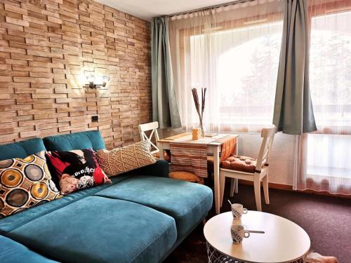 - un salon avec un canapé bleu et un mur en briques dans l'établissement Résidence Cheval Blanc - Le Cheval Blanc B2 - Agréable 2 pièces, vue magnifique sur la vallée MAE-7324, à Valmorel