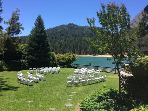 a row of white chairs on a lawn next to a lake at The Pines Resort & Conference Center in Bass Lake