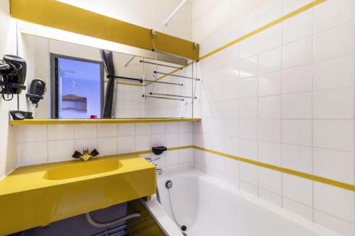La salle de bains est pourvue d'un lavabo jaune et d'une baignoire. dans l'établissement Résidence Le Hameau du Sauget - maeva Home - Appartement 2 pièces 4 personnes - Confort MAE-3944, à La Plagne Tarentaise