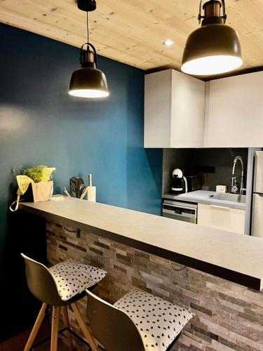 une cuisine avec deux chaises et un comptoir avec deux lumières dans l'établissement Résidence Lauzes - Les Lauzes 43 - Magnifique duplex, moderne et chaleureux MAE-4034, à Valmorel