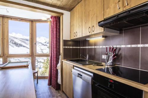 Il comprend une cuisine équipée d'une cuisinière. four supérieur à côté d'une fenêtre dans l'établissement Résidence Cheval Blanc - Le Cheval Blanc C3 - Splendide appartement offrant une vue magnifique MAE-6334, à Valmorel