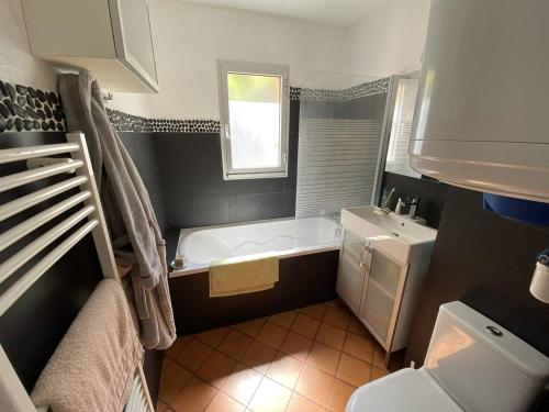 une salle de bain avec une baignoire, des toilettes et un lavabo dans l'établissement Belle vue arborée dans résidence au calme, plage à pied, à Saint-Elme