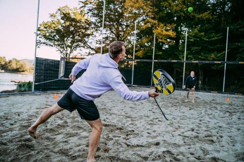 a man holding a tennis racket on a tennis court at NOI Resort SPA - woda i las in Tęgoborze