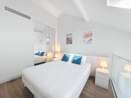 - une chambre blanche avec un grand lit blanc et des oreillers bleus dans l'établissement Nestor&Jeeves - ECLAT NICOIS - Central - Near beach, à Nice