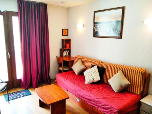 ein Wohnzimmer mit einem roten Sofa und einem Tisch in der Unterkunft Résidence Pic Du Midi - 2 Pièces pour 4 Personnes 624 in La Mongie