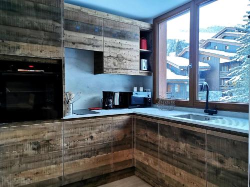 Il comprend une cuisine avec des murs en bois et une grande fenêtre. dans l'établissement Résidence Ruisseau - Le Ruisseau 25 - Très bel Appartement 3 pièces proches des pistes MAE-4594, à Valmorel