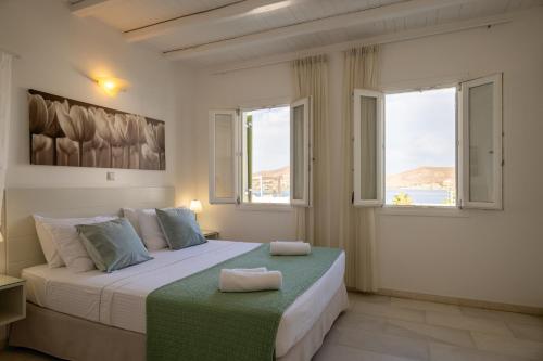 1 dormitorio con 1 cama grande y 2 ventanas en Anthos Apartments, en Naousa