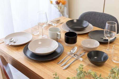 a wooden table with black and white plates and silverware at Kamata Smile House - 蒲田すまいるハウス in Tokyo