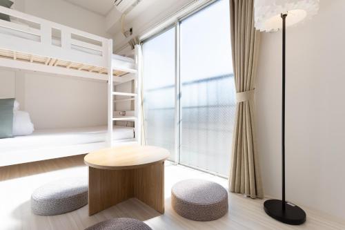 a bedroom with bunk beds and a table and a stool at Kamata Smile House - 蒲田すまいるハウス in Tokyo