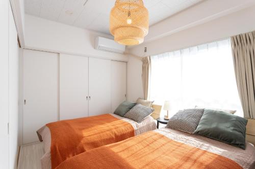 two beds in a room with a window at Kamata Smile House - 蒲田すまいるハウス in Tokyo
