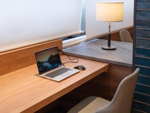 a laptop computer sitting on a desk with a lamp at APA Hotel STAY Toyama in Toyama