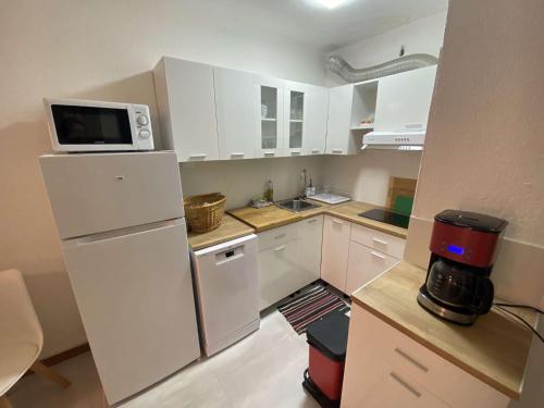 a kitchen with white cabinets and a white refrigerator at Bel appartement climatisé en rez de jardin, plage à 200 m, idéal vacances in Saint-Elme