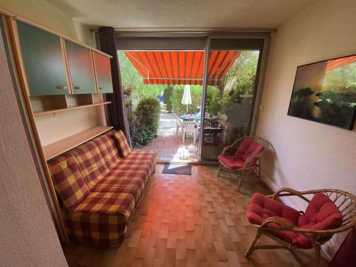 - un salon avec un canapé, des chaises et une porte coulissante en verre dans l'établissement Bel appartement climatisé en rez de jardin, plage à 200 m, idéal vacances, à Saint-Elme