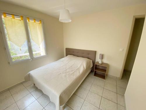 une chambre avec un lit blanc et une fenêtre dans l'établissement Vue mer au coeur de Saint Mandrier, 3 chambres, climatisation, wifi (fibre), à Saint-Mandrier-sur-Mer