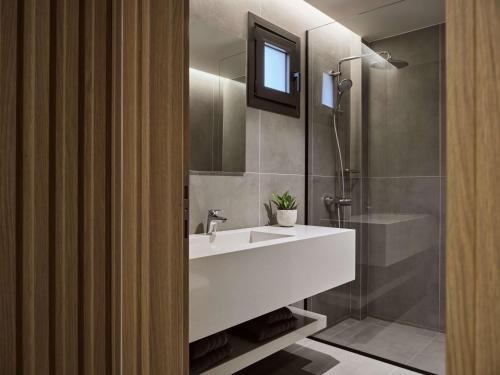 y baño con lavabo blanco y ducha. en Elounda Palm Hotel & Suites en Eloúnda
