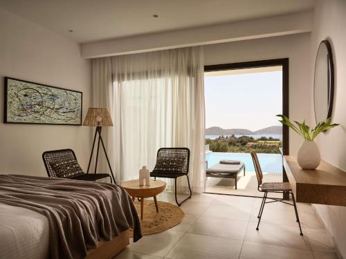 a bedroom with a bed and a table and chairs at Elounda Palm Hotel & Suites in Elounda