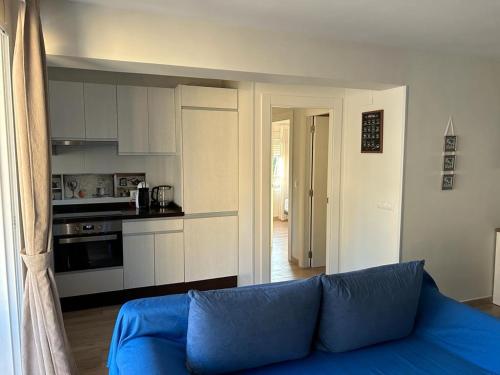 a living room with a blue couch and a kitchen at Edificio Albires in Albir