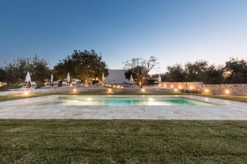 ein Schwimmbad mitten im Garten nachts in der Unterkunft Mandolario Trulli Resort in Martina Franca