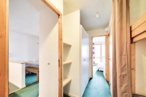 Cette chambre dispose d'un couloir avec moquette verte et d'une table. dans l'établissement Résidence Le Hameau du Sauget - maeva Home - Appartement 2 pièces 7 personnes - Sélection MAE-2914, à La Plagne Tarentaise